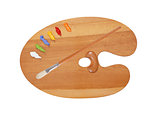 wooden art palette with blobs of paint and a brush on white back