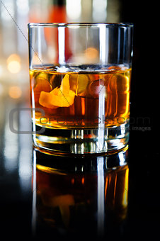 Glass of whiskey with ice cubes and fruits