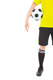  a soccer player holding a ball near waist