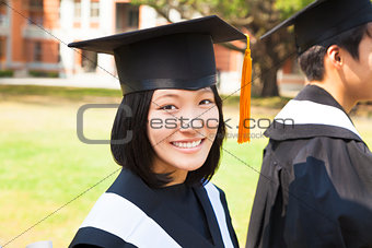 beautiful female college graduate with classmates at ceremony