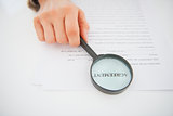 Closeup on business woman holding magnifying glass in front of i
