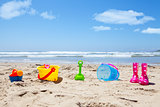 Colorful plastic toys and gumboots on beach sand
