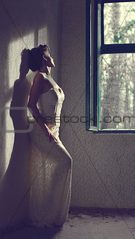 Sexy girl posing in an old room near the window on a sunny day