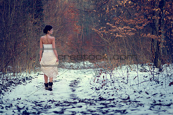 Lonely girl in white beautiful lace dress walking in a forest
