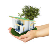 Hands holding a small house with land