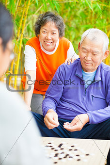 seniors play weiqi with friends in the park
