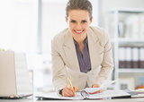 Smiling business woman working in office with documents