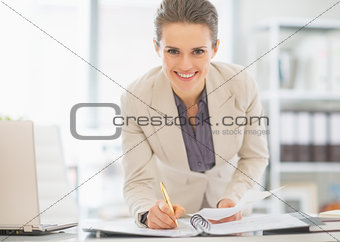 Smiling business woman working in office with documents
