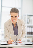 Portrait of smiling business woman working in office with docume