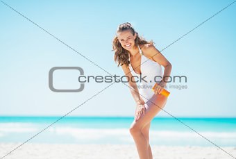 Young woman on beach applying sun block creme