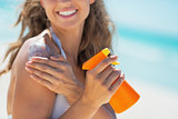 Closeup on smiling young woman with sun screen creme