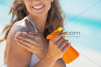 Closeup on smiling young woman with sun screen creme