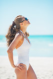 Young woman in sunglasses tanning on beach