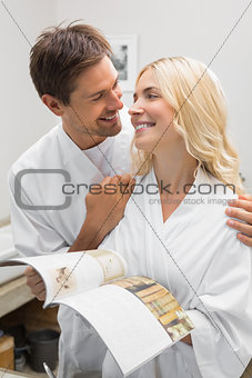 Happy couple with recipe book looking at each other in kitchen