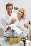 Happy young couple with recipe book in kitchen