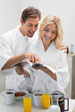 Happy young couple with recipe book in kitchen