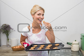 Smiling young woman with a tray of cookies in kitchen