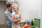 Happy couple embracing while preparing food in kitchen