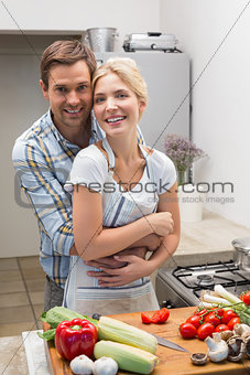 Portrait of a couple embracing while preparing food in kitchen