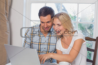 Smiling couple using laptop in kitchen
