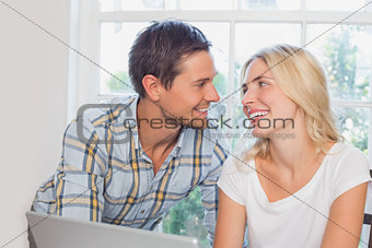 Smiling young couple looking at each other at home