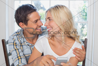 Loving couple reading text message together at home
