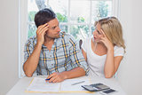 Worried couple with financial documents and calculator