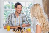 Couple playing chess while having orange juice at home