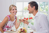 Happy young couple toasting wine glasses over food
