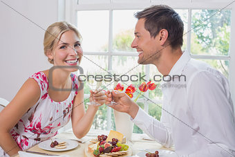 Happy young couple toasting wine glasses over food