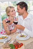 Loving couple with wine glasses looking at each other at dining table