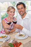 Loving couple with wine glasses sitting at dining table