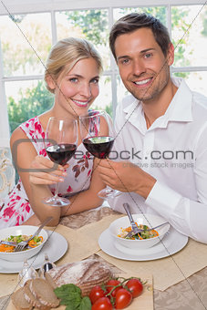 Loving couple with wine glasses sitting at dining table