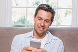 Casual man reading text message on sofa