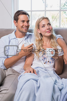 Relaxed couple with coffee cups in living room at home