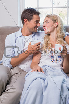 Relaxed loving young couple with coffee cups in living room