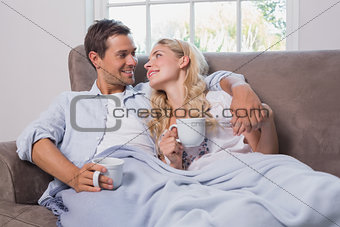 Relaxed loving young couple with coffee cups in living room