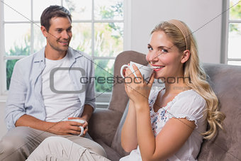 Couple with coffee cups sitting in living room