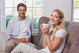 Portrait of relaxed couple with coffee cups in living room