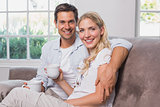 Relaxed loving couple with coffee cups sitting on sofa