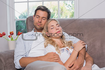 Relaxed loving couple sitting on sofa with eyes closed