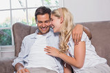 Relaxed cheerful loving young couple sitting on sofa