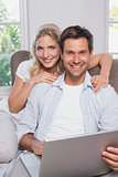 Portrait of casual couple using laptop in living room