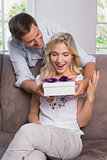 Smiling man surprising cheerful woman with gift