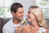 Cheerful loving couple with champagne flutes at home