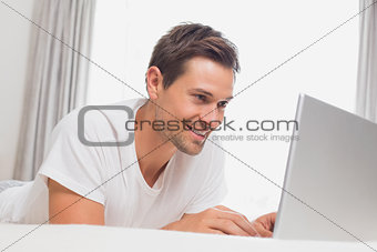 Relaxed casual man using laptop in bed
