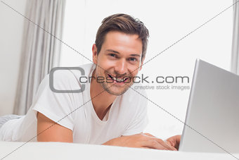 Portrait of relaxed casual man using laptop in bed
