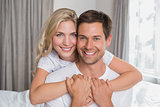 Loving woman embracing man from behind at home