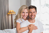 Loving woman embracing man from behind at home