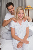 Man massaging woman's shoulders in bed